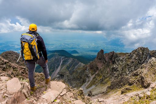 A hiker with a backpack standing on the top of the mountain