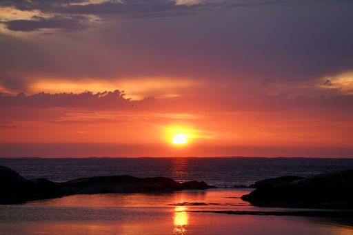 Vibrant sunset over beach water as sun sets on horizon