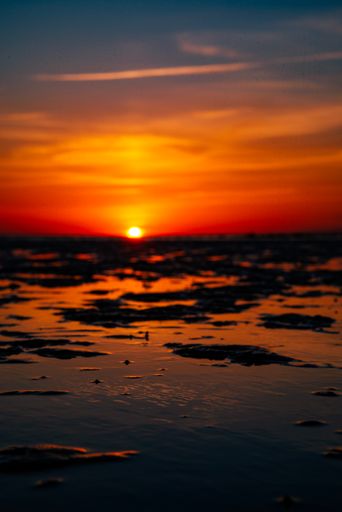 A Sunset over the ocean viewed from a sandy beach