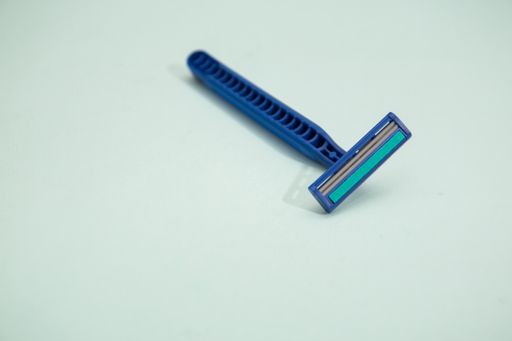 A top view of a dark blue razor with a light blue background