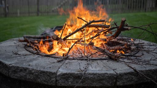 A fire pit with stacked logs on grass