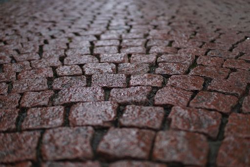 A high angle shot of old and small red-brick tiled ground with reflection of light on it