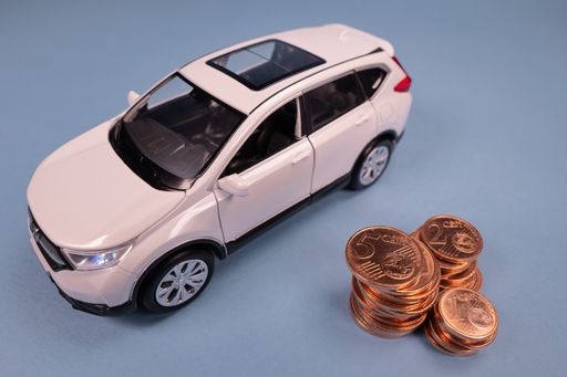 Car model and coins stack on blue background