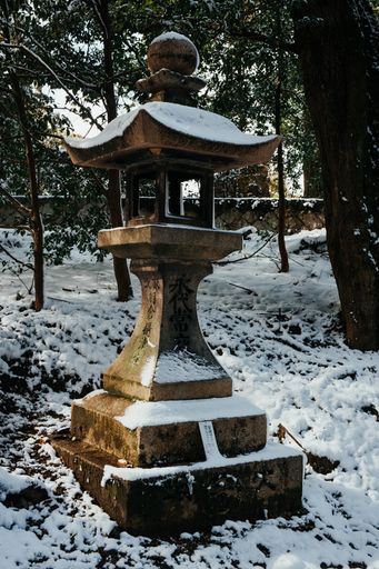 The Ancient style traditional Japanese lantern covered in rare winter snow at Fushimi Inari Shrine in Kyoto Japan.