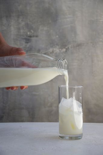 Milk is being poured into the glass of ice.