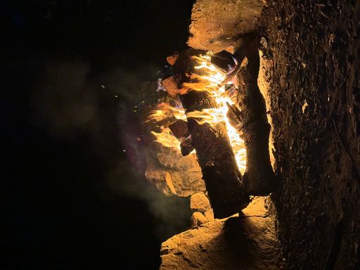 A bonfire blazing on a sandy beach near rocks