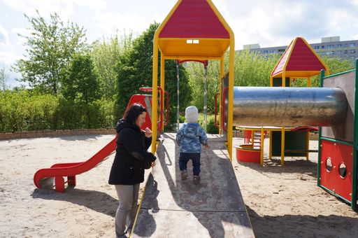 A woman and a child at a playground on a sunny cold day