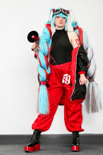 A female cosplayer dressed as an anime character with blue hair and a megaphone