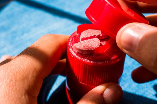 A closeup shot of hands holding a red pill cutter