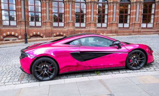 A pink McLaren 570S car parked on the street in London, UK.