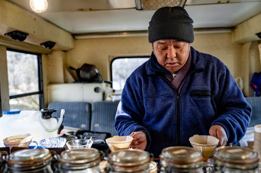 Japanese man making pourover coffee in a converted school bus coffee shop. Winter time in Fuji Fujikawaguchiko Japan.