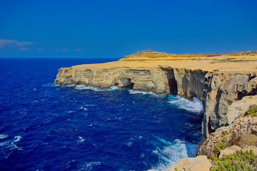 A rocky shore and ocean view from a cliff by the sea. Gozo, Malta
