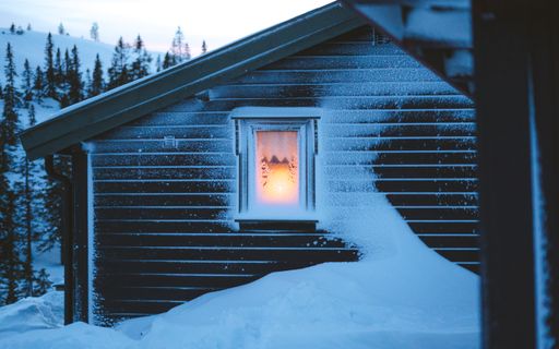 A beautiful scenery of a village with wooden cabins covered with snow surrounded by fir trees in Norway