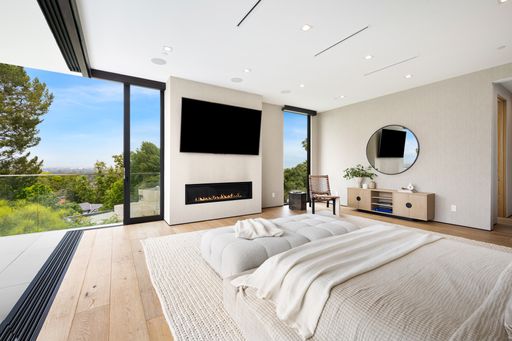 A modern, expansive Bedroom with a forest view through the window