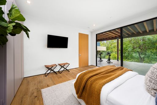 A Bright white bedroom with large windows and hardwood floors