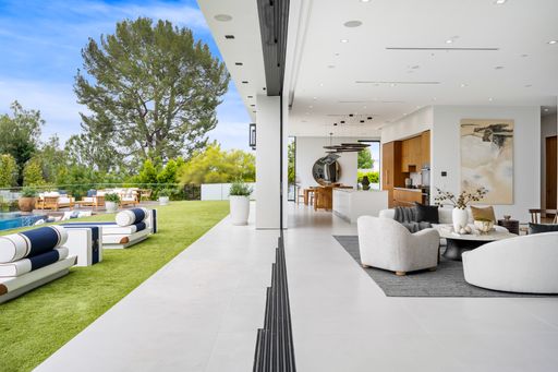 An Open living area seamlessly connects to backyard with stylish furniture and a pool