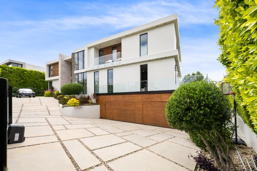 A luxurious house near a green fence on a sunny day