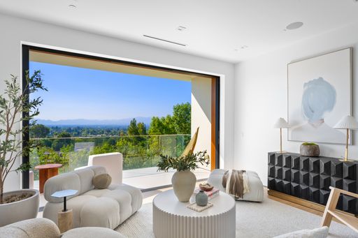 A Modern living room with white furniture and expansive windows framing mountain views