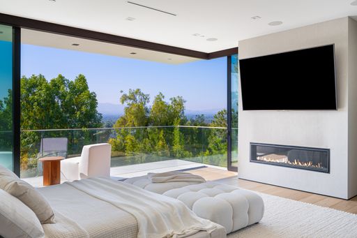 A Modern bedroom with white furniture, large windows, a TV, a balcony with a view and white bedding