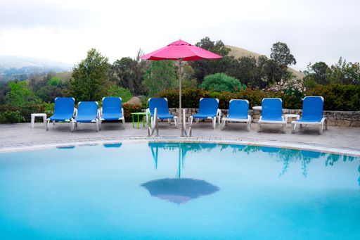 A swimming pool with a red umbrella and lounge chairs