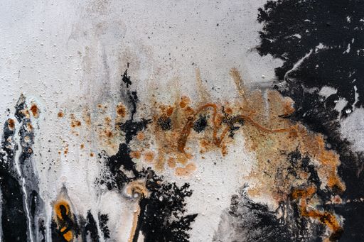 A closeup image of a textured wall with black and brown paint splashes