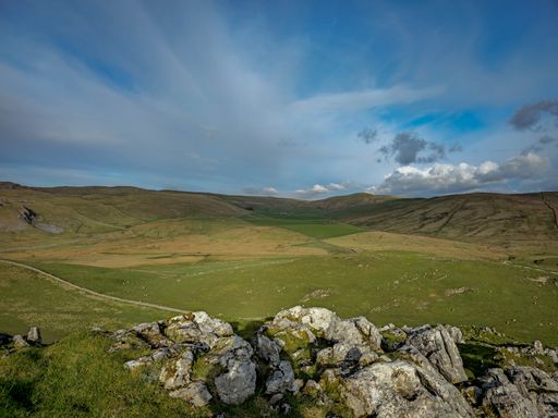 A scenic view of lush green fields and rolling hills under a partly cloudy sky in Skipton