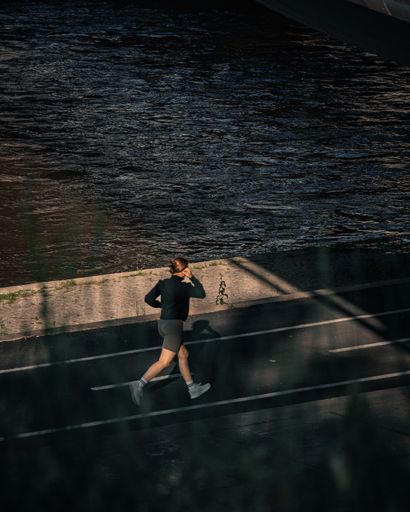 A woman jogging by the water at dusk
