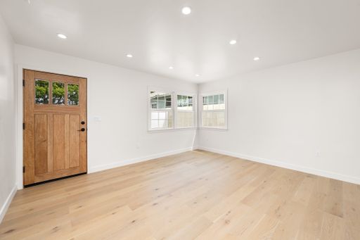 A vacant living room with wooden floors, white walls, and hardwood flooring