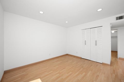 Empty room with white walls, hardwood flooring, and an open door
