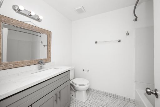 Tiny bathroom with white toilet under large mirror