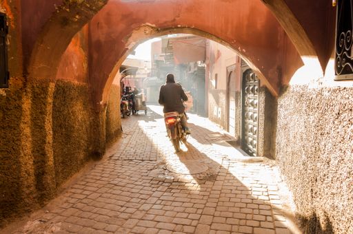 A scooter driving through a smokey street in the Medina of Marrakech, Morocco