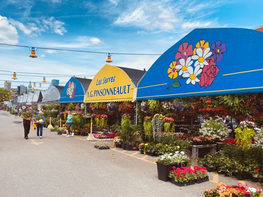 A flower shop in a town on a roadside with pedestrians passing by
