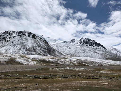 A scenic mountain range with snow and grass in the foreground