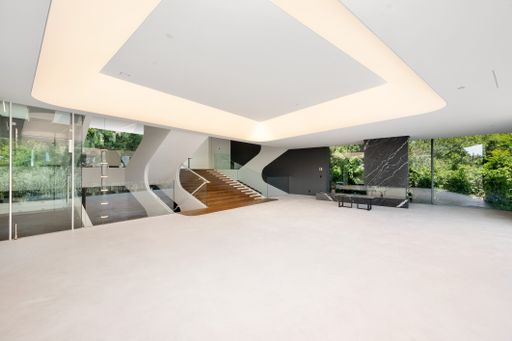 A Spacious empty living room with black marble benches and a staircase