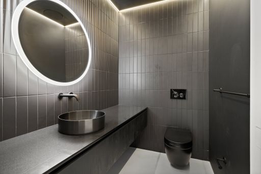 Circular mirror above sink in contemporary bathroom with oversized mirrors