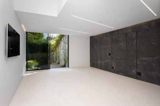 Minimalist room with concrete walls, white floors, and wall-mounted TV