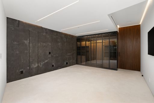 Spacious room with concrete walls and elevator area in the background