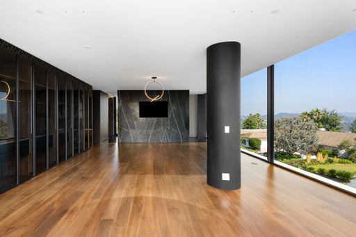 A room with a wall-mounted TV and tall windows