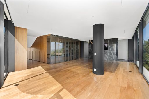 Spacious room with hardwood flooring, expansive windows, and a lengthy wood stove