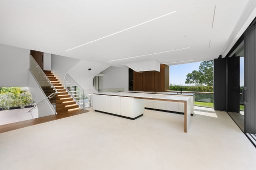 A white kitchen with staircase leading to balcony