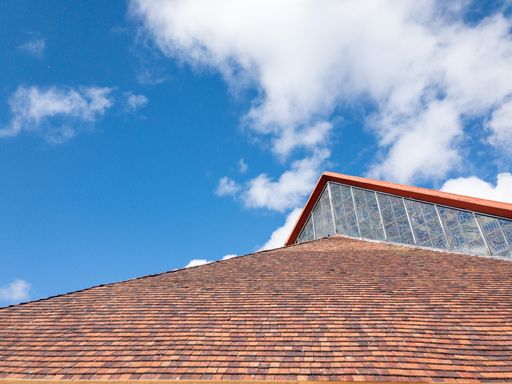 A closeup of a red roof with attic under the clear blue sky