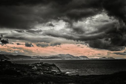A shot of dark clouds soar above the ocean at sunset