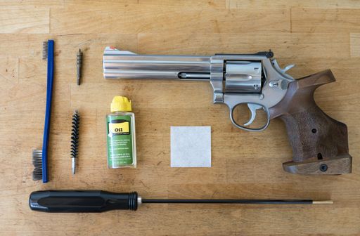 Detail of the cleaning and maintenance tools of a 357 magnum or 38 special revolver-type pistol. Everything on a wooden table