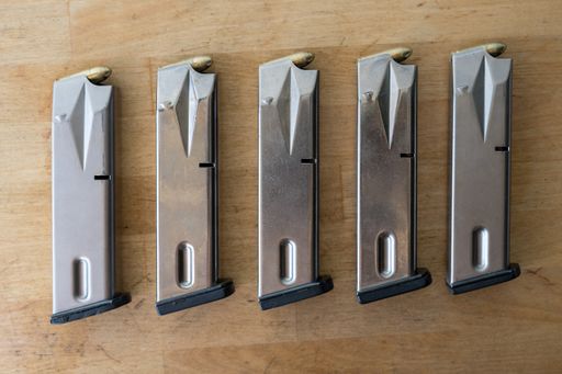 Detail of 5 9mm pistol magazines. The magazines are fed with bullets and lined up on a wooden table