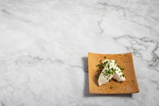 A delicious appetizer on a small wooden plate on a marble texture table