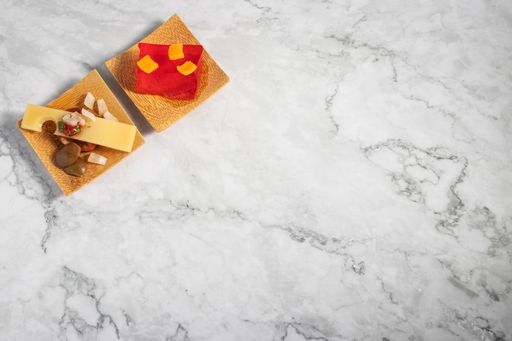 A top view of delicious appetizers on a small wooden plate on a marble texture table