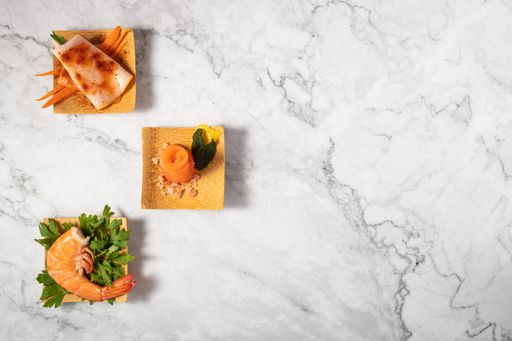 A top view of delicious appetizers on a small wooden plate on a marble texture table