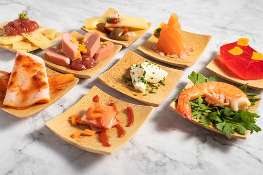 A closeup of delicious appetizers on a small wooden plate on a marble texture table