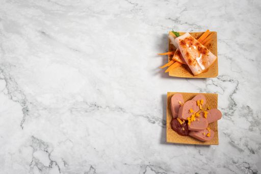 A top view of delicious appetizers on a small wooden plate on a marble texture table
