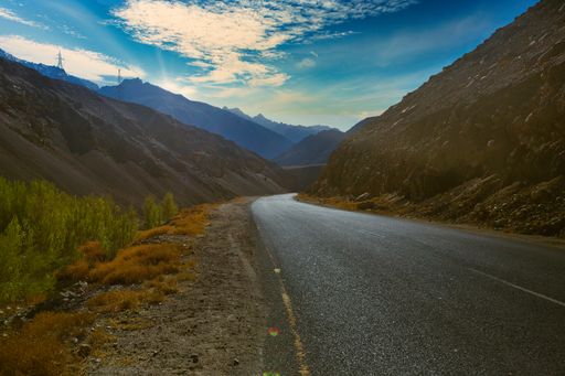 A mountain landscape with grassy slopes and winding roads marked with yellow lines